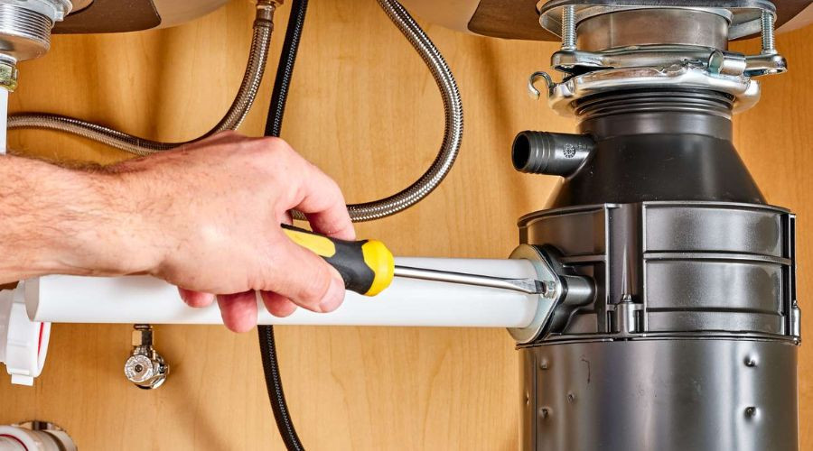 Plumber using a screwdriver on a garbage disposal
