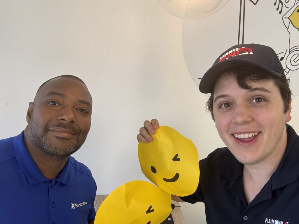 PlumbingPro technician and a guest smiling with yellow smiley-face balloons