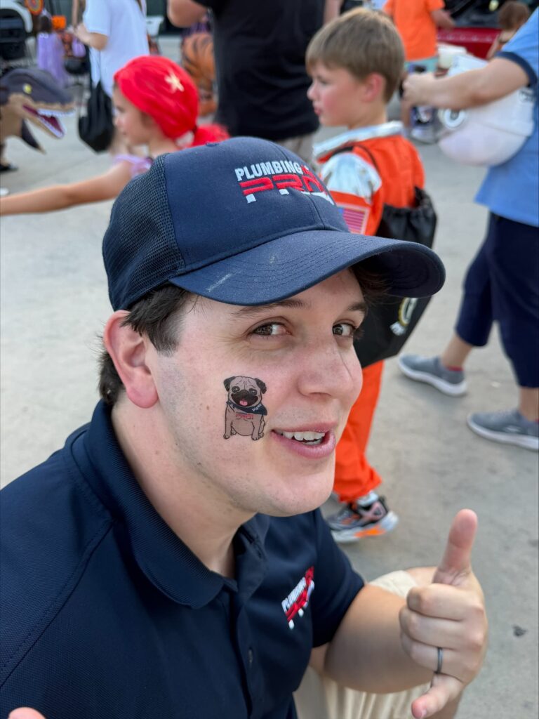 Austin plumber with company sticker on face smiling during community outreach event