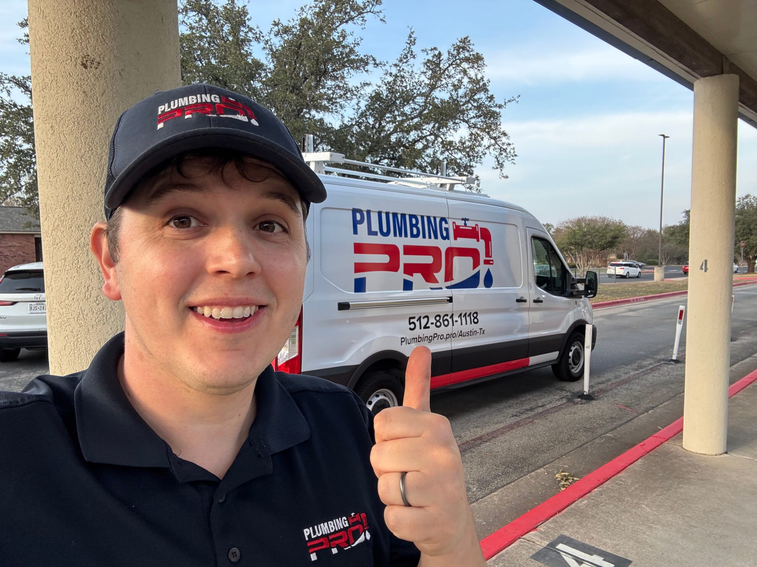 Smiling PlumbingPro technician giving a thumbs up in front of a PlumbingPro van