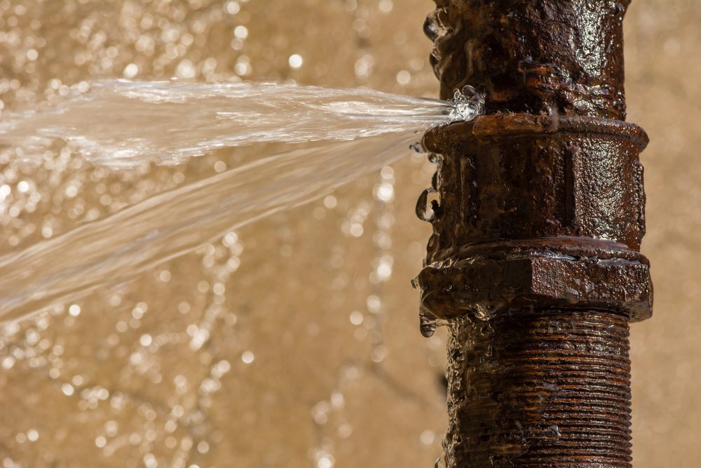Water spraying from a hole in a rusted pipe