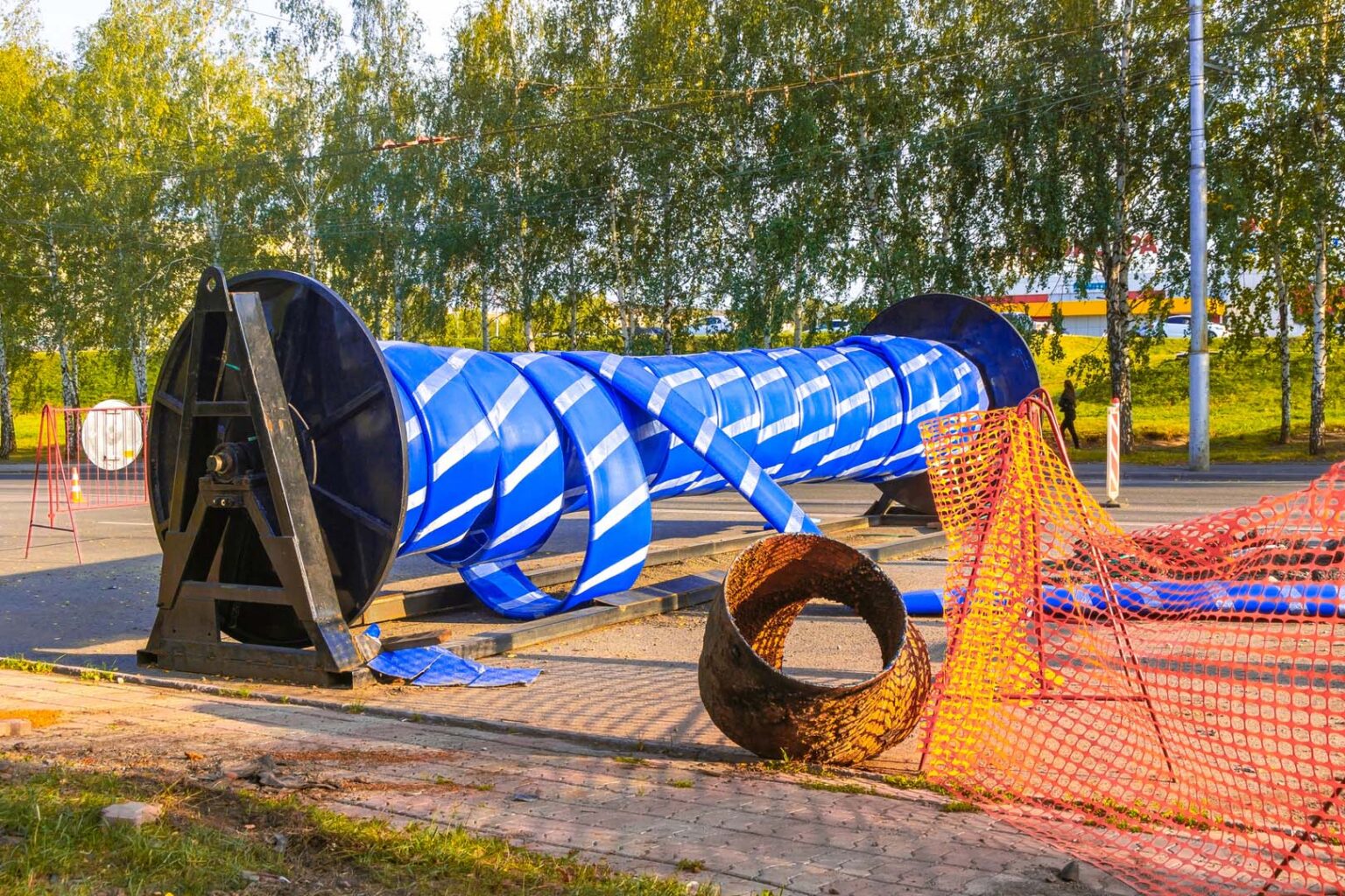 Blue spiral-wound pipe liner on a large reel at a pipe relining work site