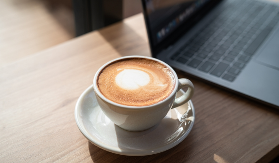 Cup of coffee next to a laptop