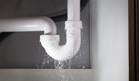 Water leaking from a white P-trap under a sink