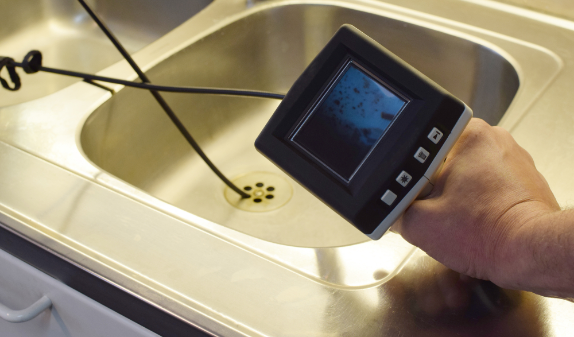 Camera inspection screen held over a sink drain
