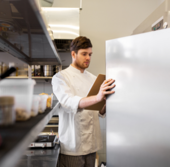 Chef with a clipboard checking a commercial refrigerator