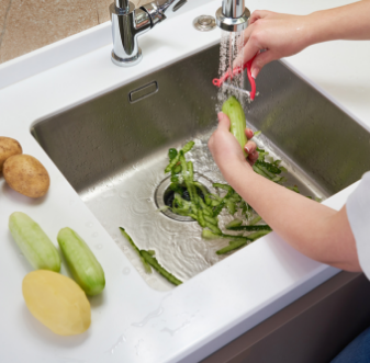 Rinsing vegetables over a sink with a garbage disposal