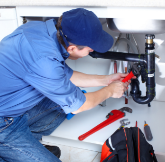 Plumber working on pipes under a kitchen sink