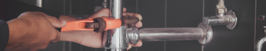 Plumber tightening a pipe fitting with a wrench