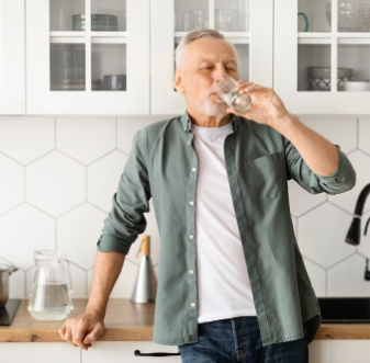 Man drinking a glass of water in his kitchen