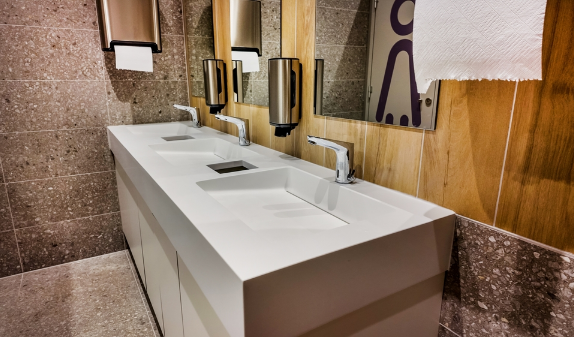Commercial restroom with a long stone sink counter