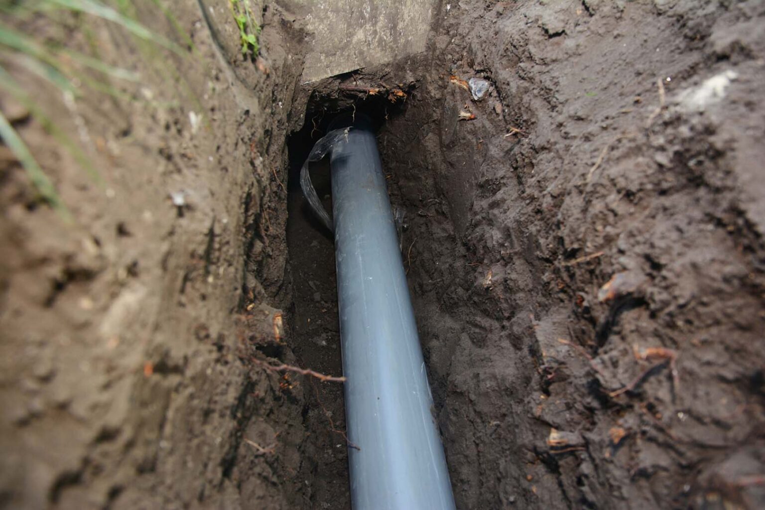 New gray PVC sewer pipe laid in an excavated trench