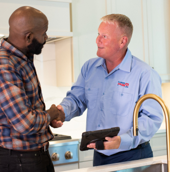 PlumbingPro technician shaking hands with a homeowner in a kitchen