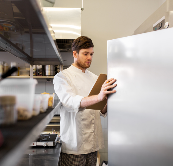 Chef with a clipboard checking a commercial refrigerator
