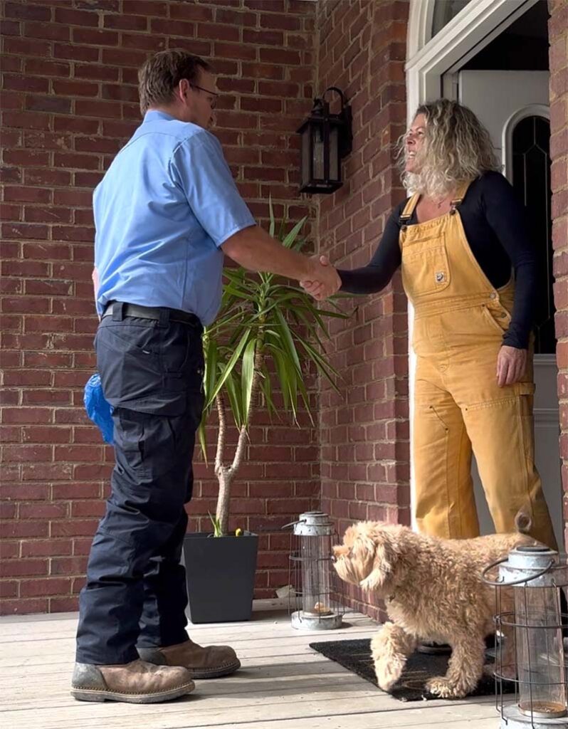 Technician greeting a homeowner and her dog at the front door