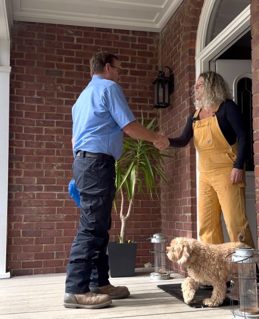 Technician greeting a homeowner and her dog at the front door