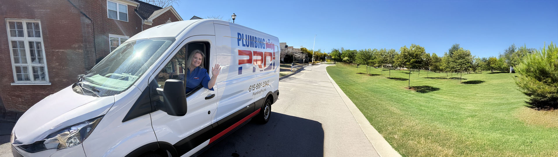 PlumbingPro service van on a road next to a green field