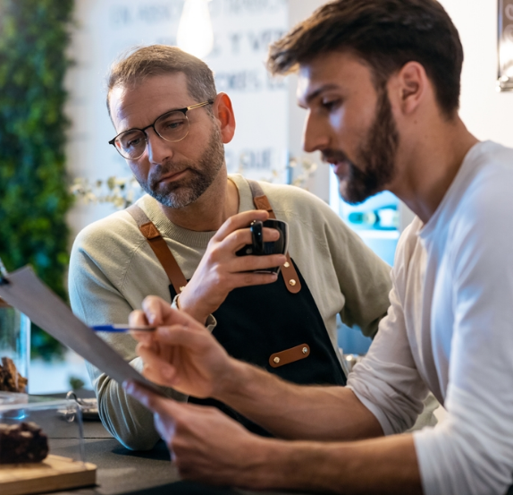 Two men reviewing paperwork in a café