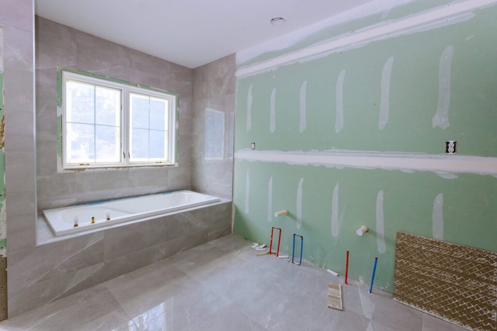 Bathroom under renovation with a new tub and exposed supply lines