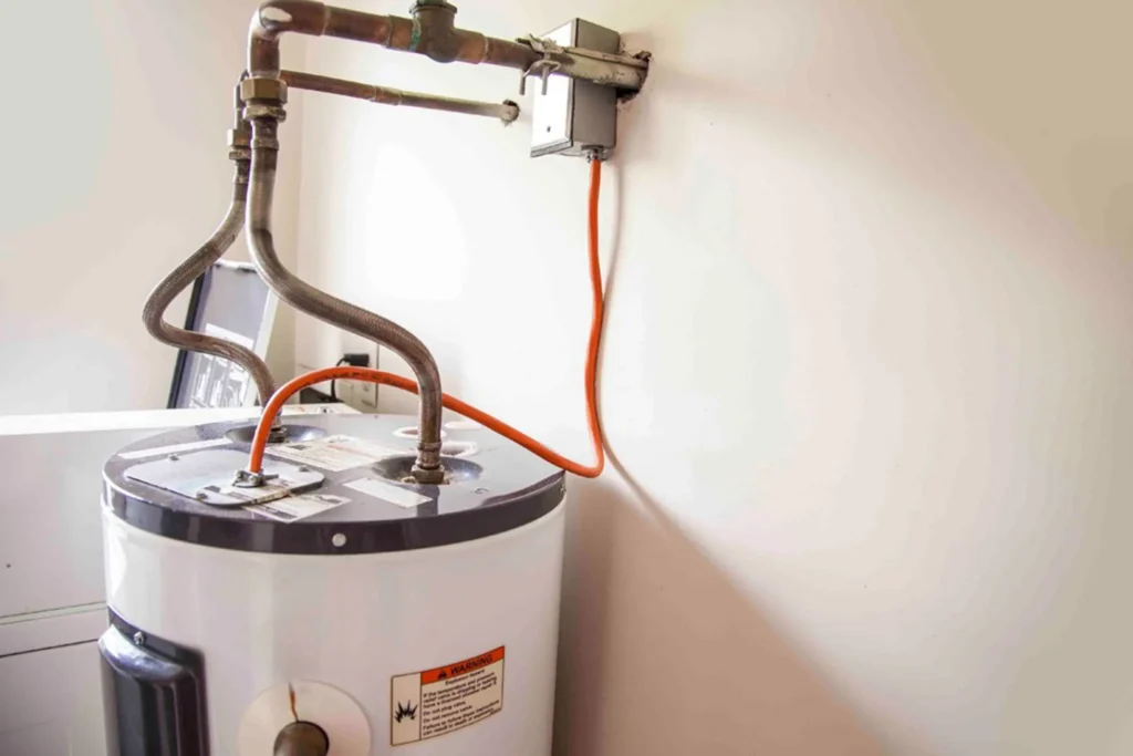 Tank water heater with copper supply lines against a wall