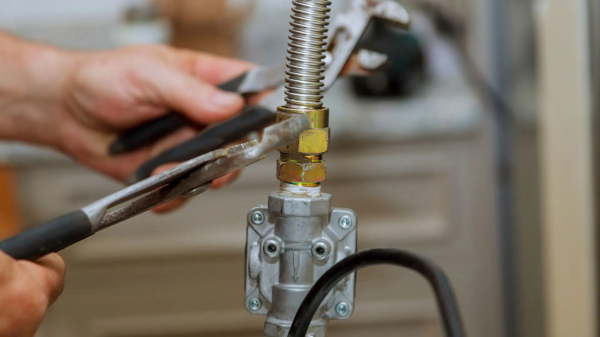 Hands tightening a flexible gas line fitting with a wrench