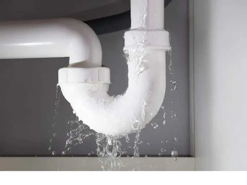 Water leaking from a white P-trap under a sink
