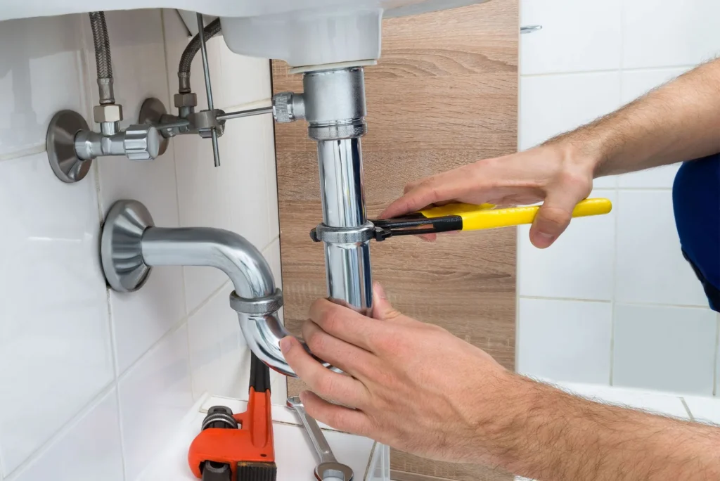 Plumber tightening a sink drain pipe with pliers