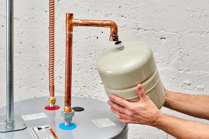 Hands installing an expansion tank on a water heater