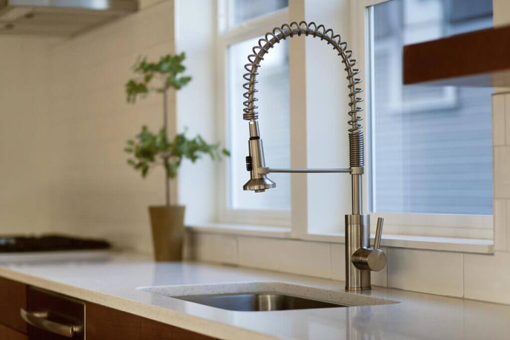 Stainless steel pull-down kitchen faucet by a window