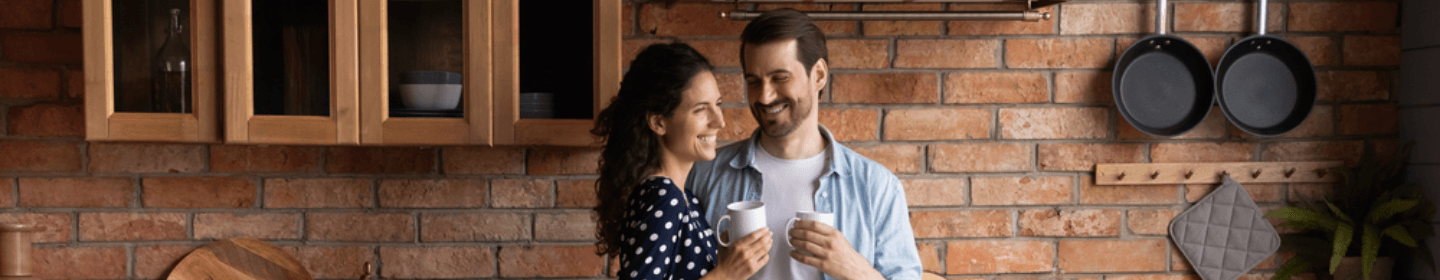 Couple smiling in a kitchen with a brick wall