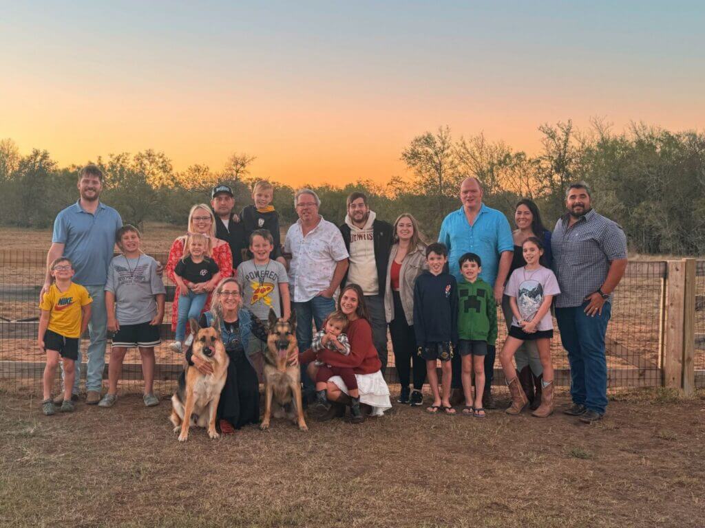 Large family group with dogs posing outdoors at sunset