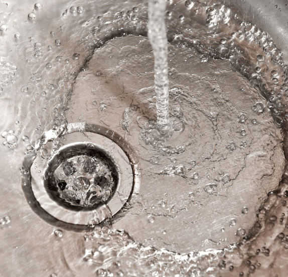 Water swirling into a stainless steel sink drain
