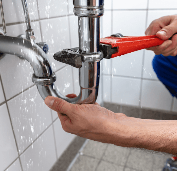 Plumber tightening a chrome P-trap with a red wrench