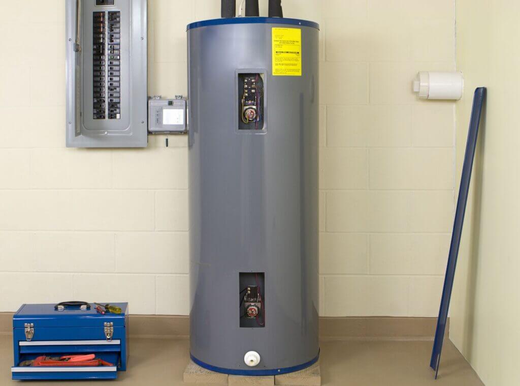 Tank water heater next to an electrical panel in a garage