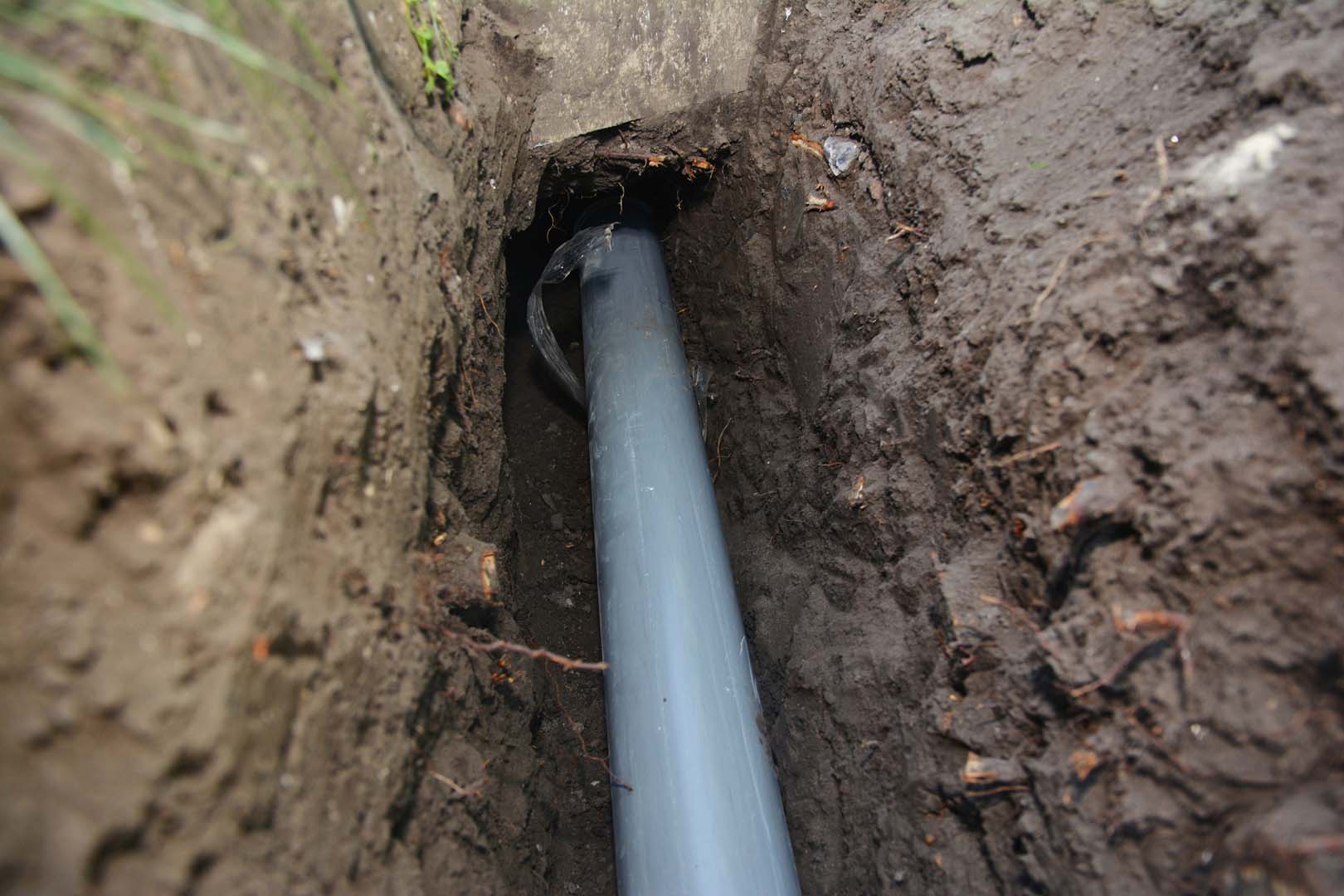 New gray PVC sewer pipe laid in an excavated trench
