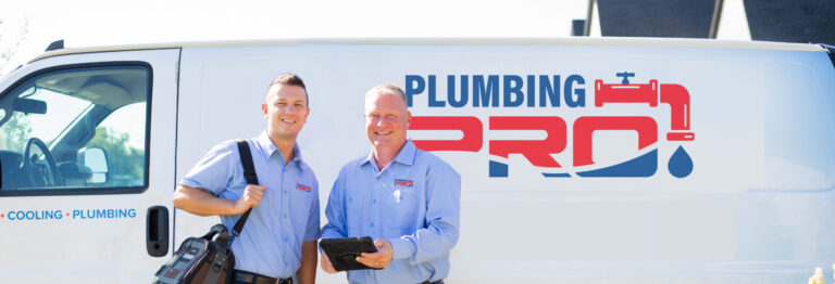 Two PlumbingPro team members standing beside a branded PlumbingPro van