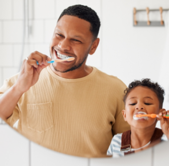 Father and son brushing their teeth in a bathroom mirror
