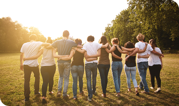 Group of friends with arms around each other in a park at sunset