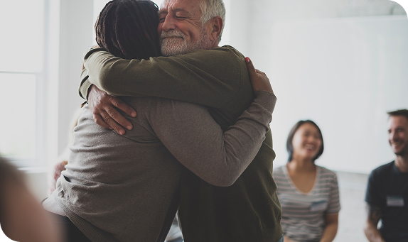 Two people sharing a warm hug in a group gathering