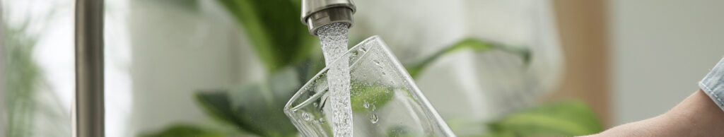 Glass being filled with water from a kitchen faucet