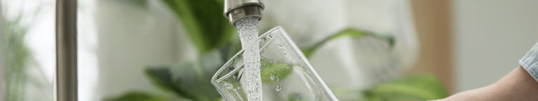 Glass being filled with water from a kitchen faucet