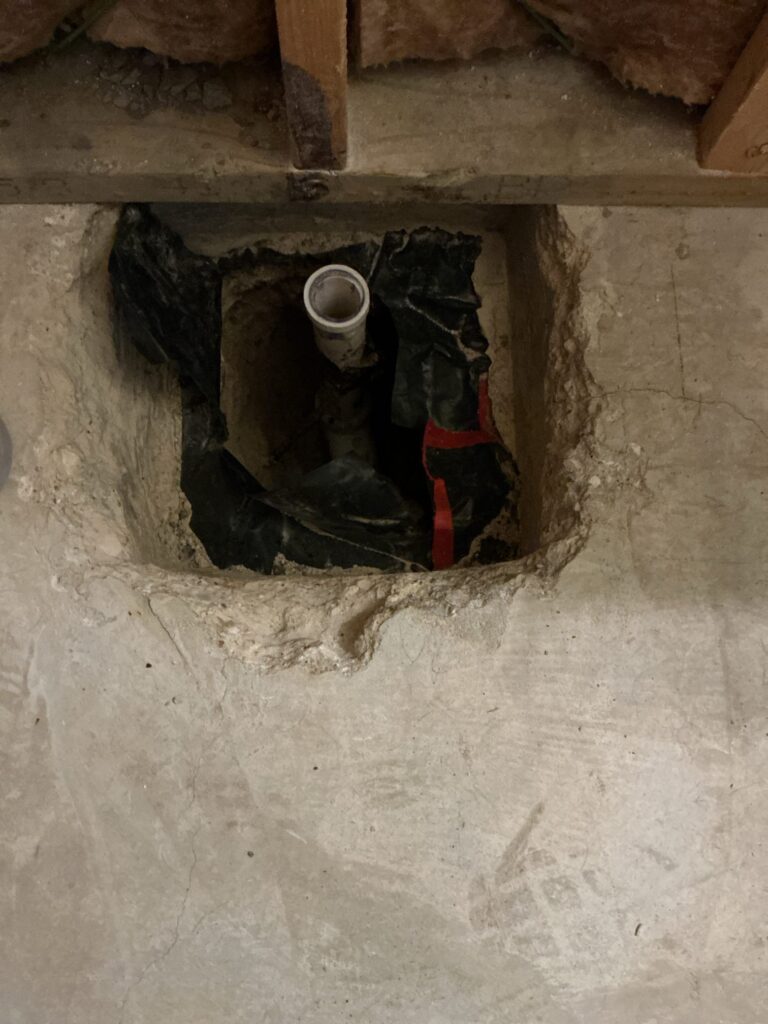 Opening cut in a concrete floor exposing an existing 1.5-inch drain pipe