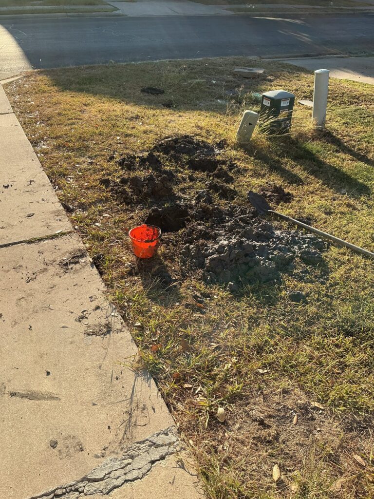 Freshly dug soil in a front yard near the sidewalk and water meter