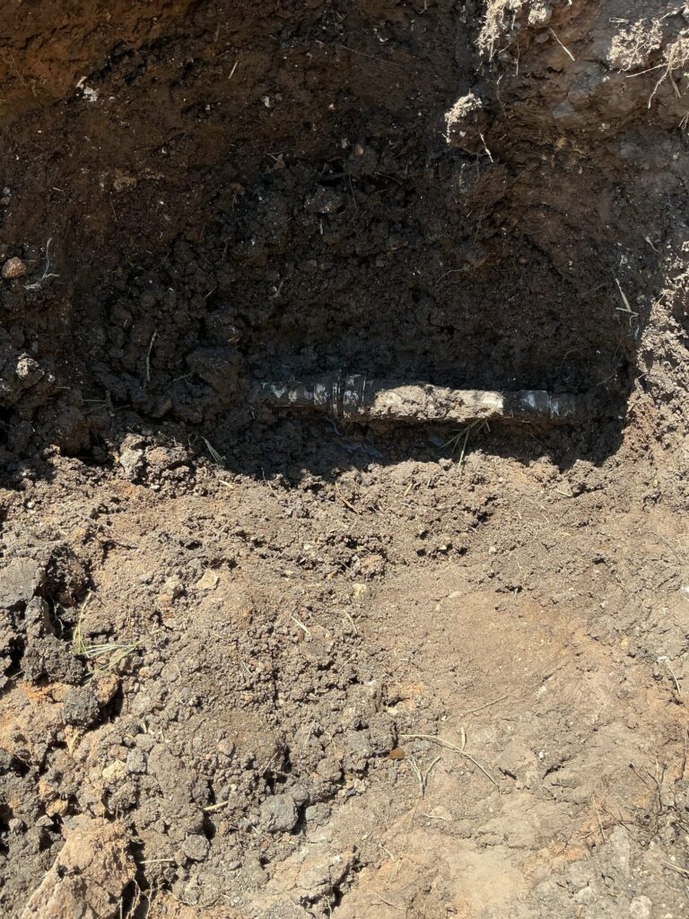 Repaired underground pipe exposed in an excavated hole