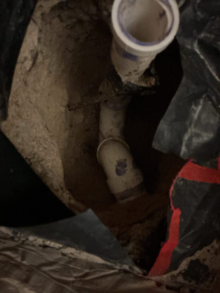 New 2-inch PVC drain pipe installed in an excavated floor before backfill