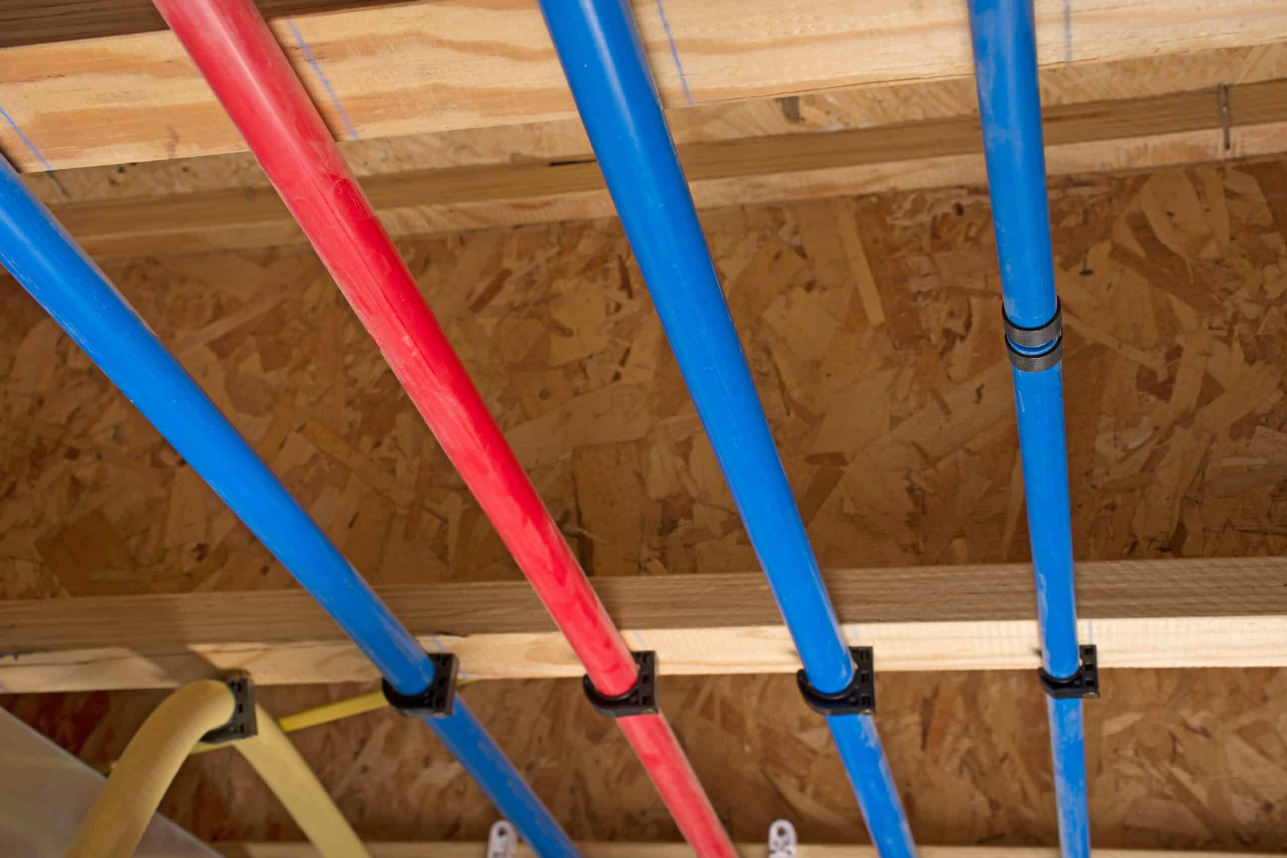 Red and blue PEX water pipes run along ceiling joists during repiping
