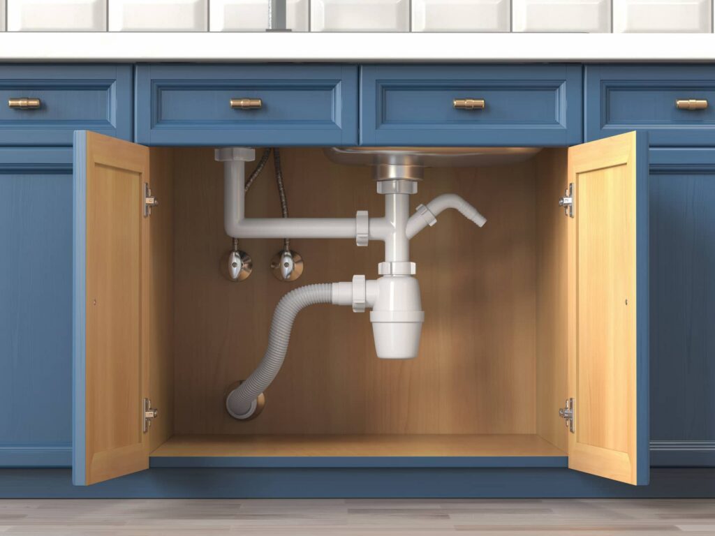 Open blue sink cabinet showing white drain pipes and a P-trap