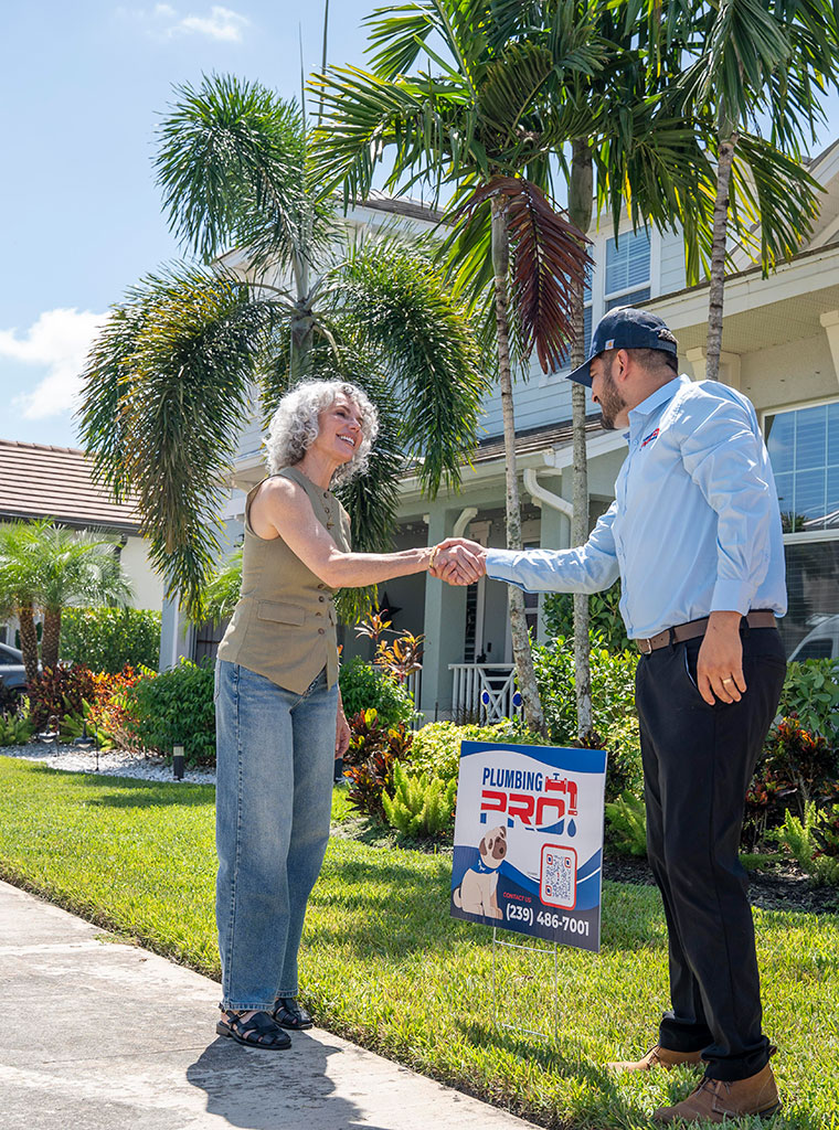 PlumbingPro technician shaking hands with a homeowner beside a PlumbingPro yard sign